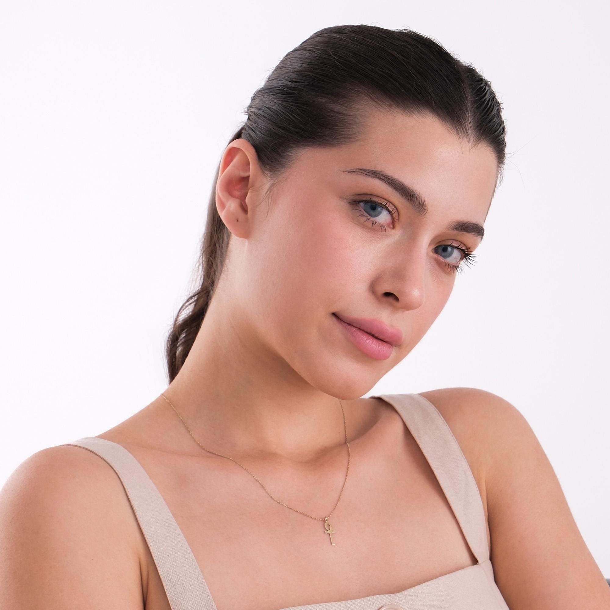 Side profile of a woman wearing a 14K solid gold Ankh necklace, highlighting the pendant’s subtle shine.