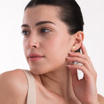 A soft, candid shot of a woman touching her ear, where 14K solid gold triple moon earrings shine subtly, adding a mystical touch.