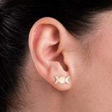 Close-up of a woman's ear wearing 14K solid gold triple moon earrings, highlighting the delicate triple moon phases in a minimalist design.