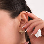 14K solid gold Witches Knot earrings shown worn by a model, highlighted by her gently raised hand and clean, minimal background.