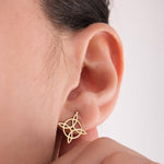Close-up of a woman's ear with 14K solid gold Witches Knot earrings, featuring a delicate interwoven symbol representing protection and unity.