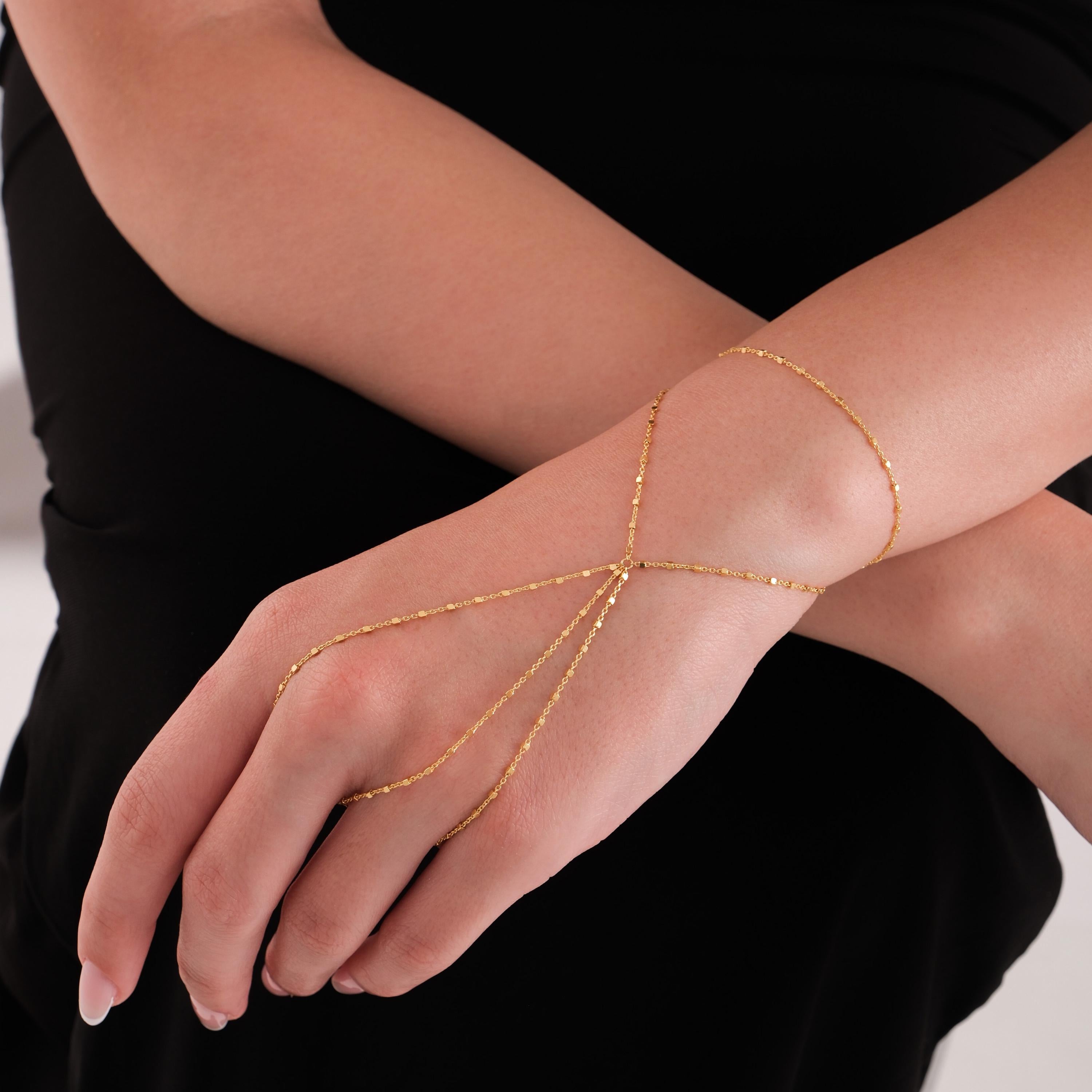 The 18K gold vermeil hand chain wraps elegantly around the wrist and fingers, styled against a black outfit for a refined, modern look.