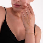 Close-up of a woman wearing an 18K gold vermeil hand chain, with delicate chains draped across the back of the hand and around the wrist.