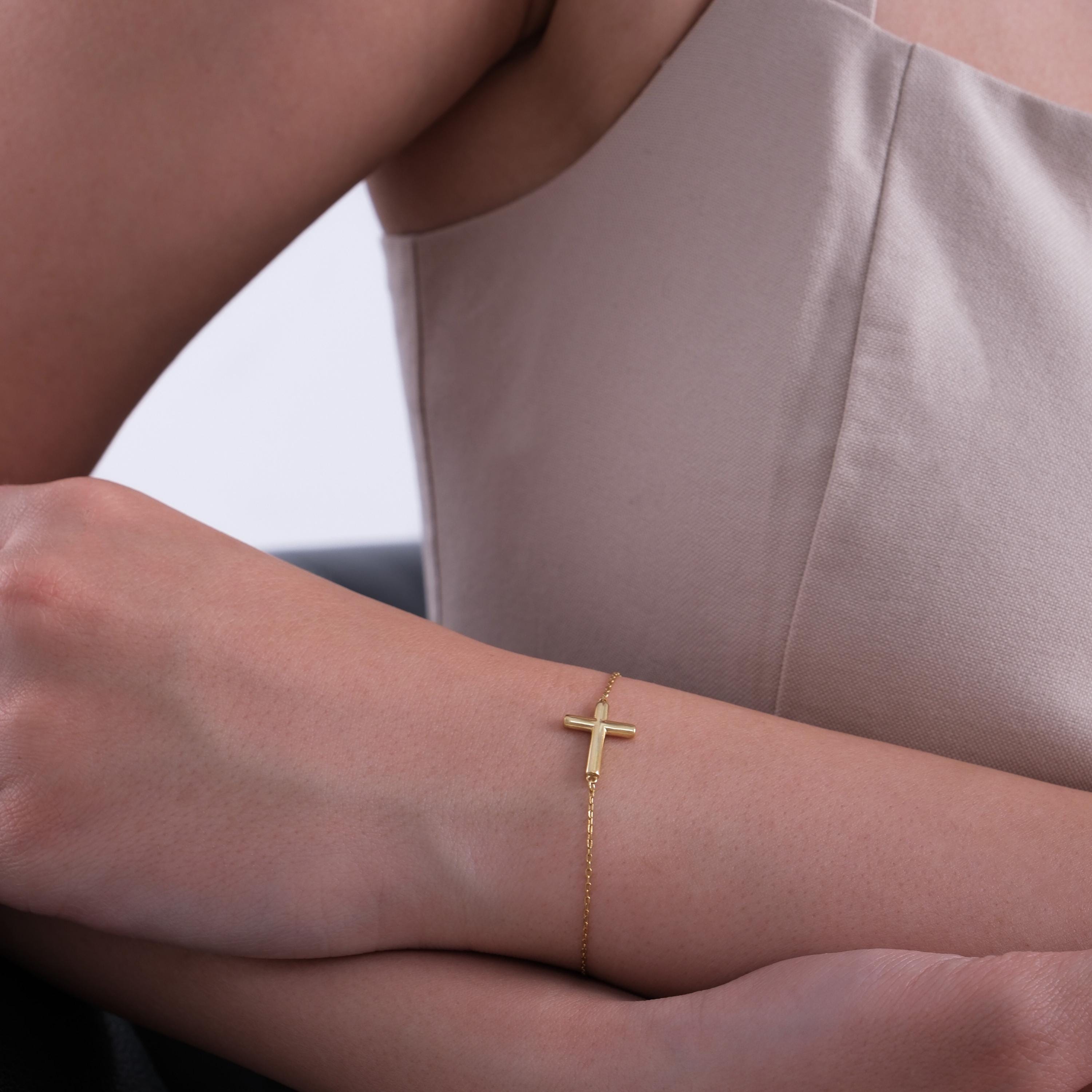 Close-up of a 14K solid gold dainty cross bracelet featuring a thick horizontal cross detail on a fine gold chain.