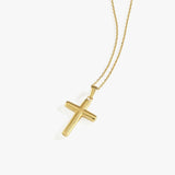 Studio shot of a 14K solid gold cross necklace on a fine chain, isolated on a white background.