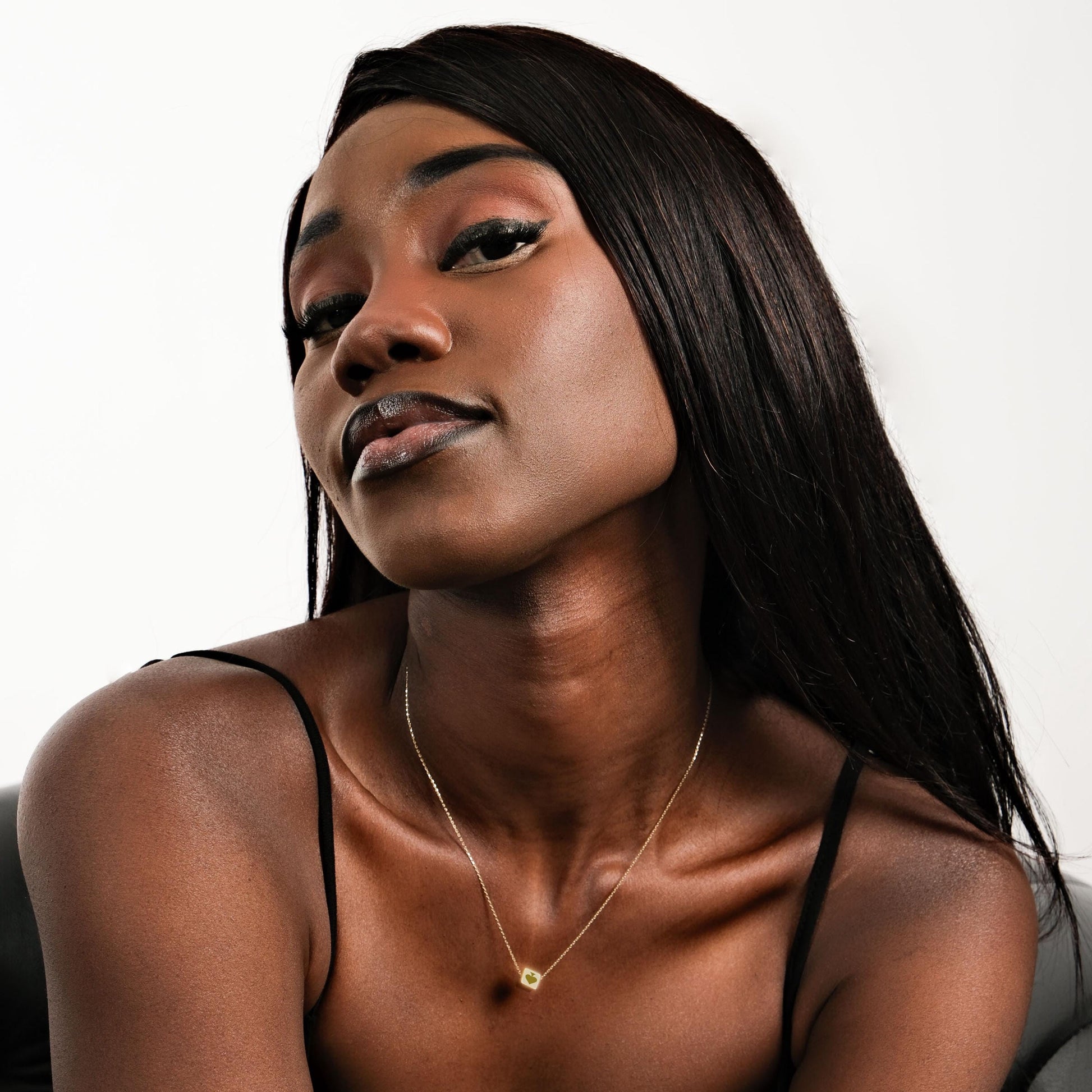 A woman with straight black hair wearing the 14K solid gold Spade Cards necklace, looking confidently at the camera.