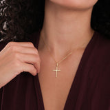 A woman wears the 18K Gold Vermeil Cross Necklace, holding the chain near her collarbone.