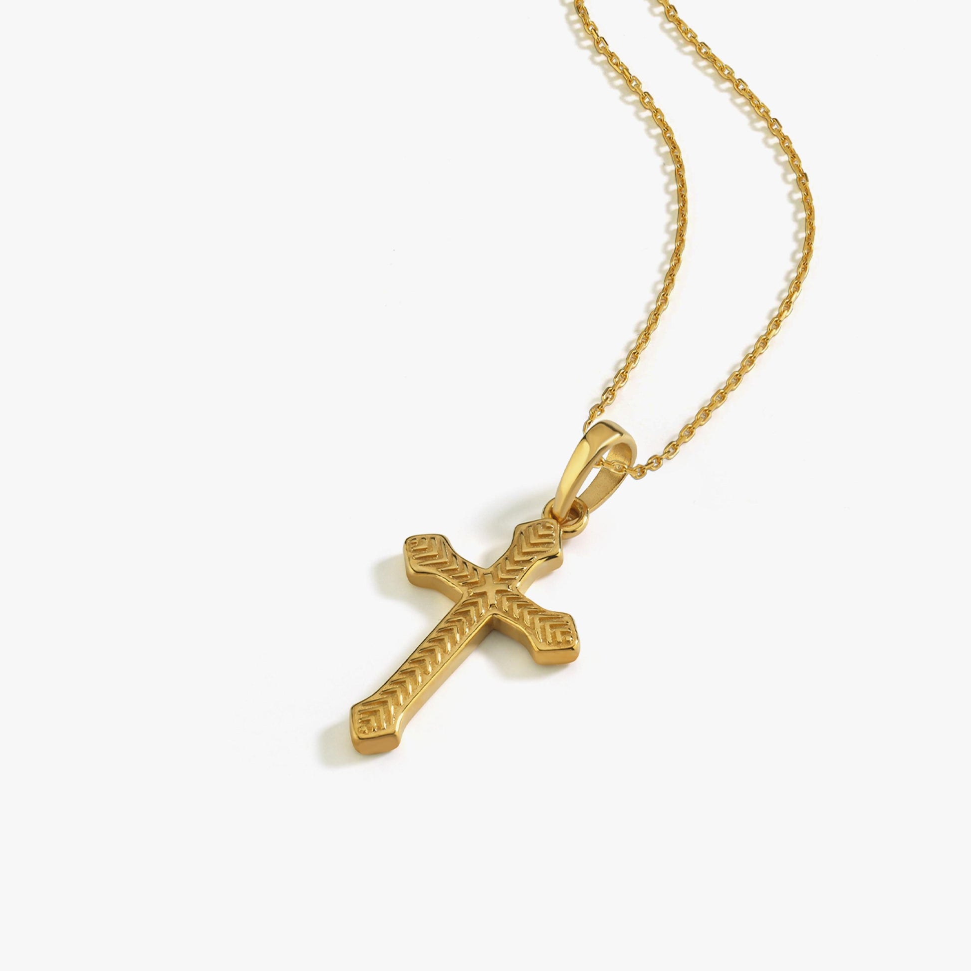 18K gold vermeil cross necklace for women laid flat with chain coiled on a white surface.