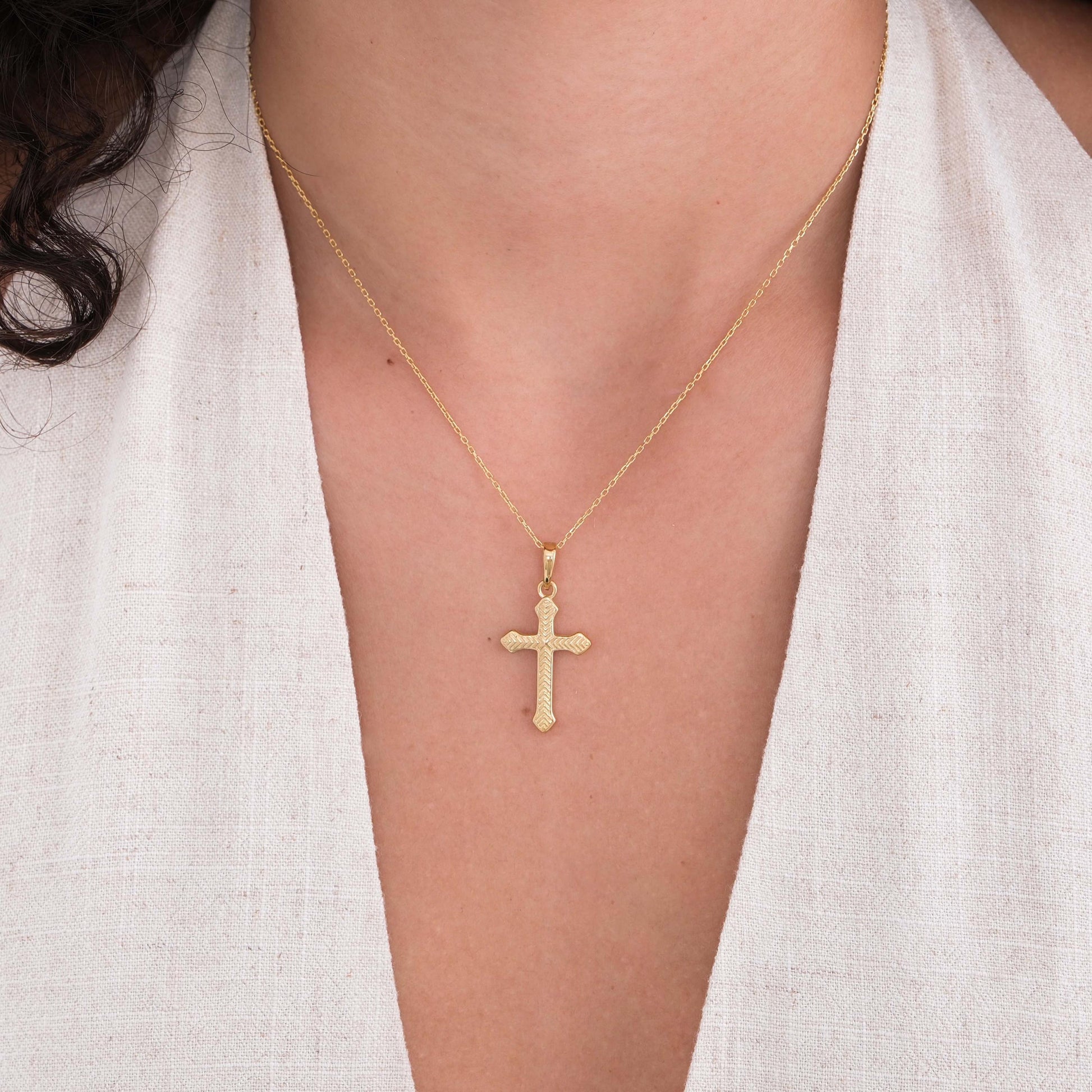 Elegant 18K gold vermeil cross necklace worn by a woman with a deep V-neck linen top.