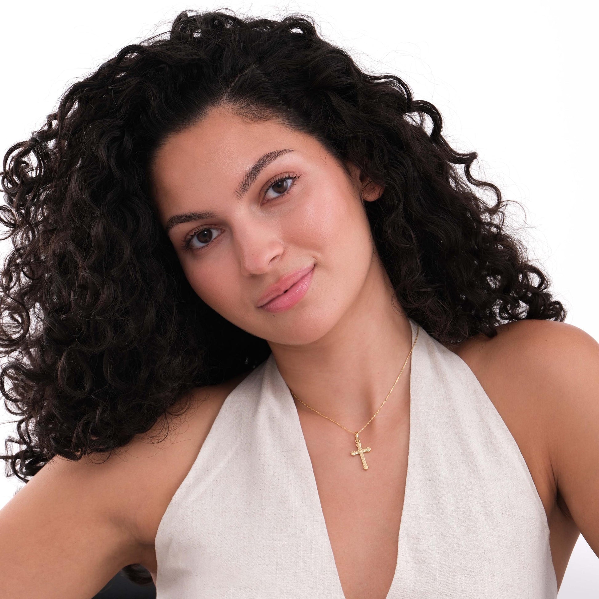 Young woman wearing an 18K gold vermeil cross necklace, styled with a sleeveless beige top.