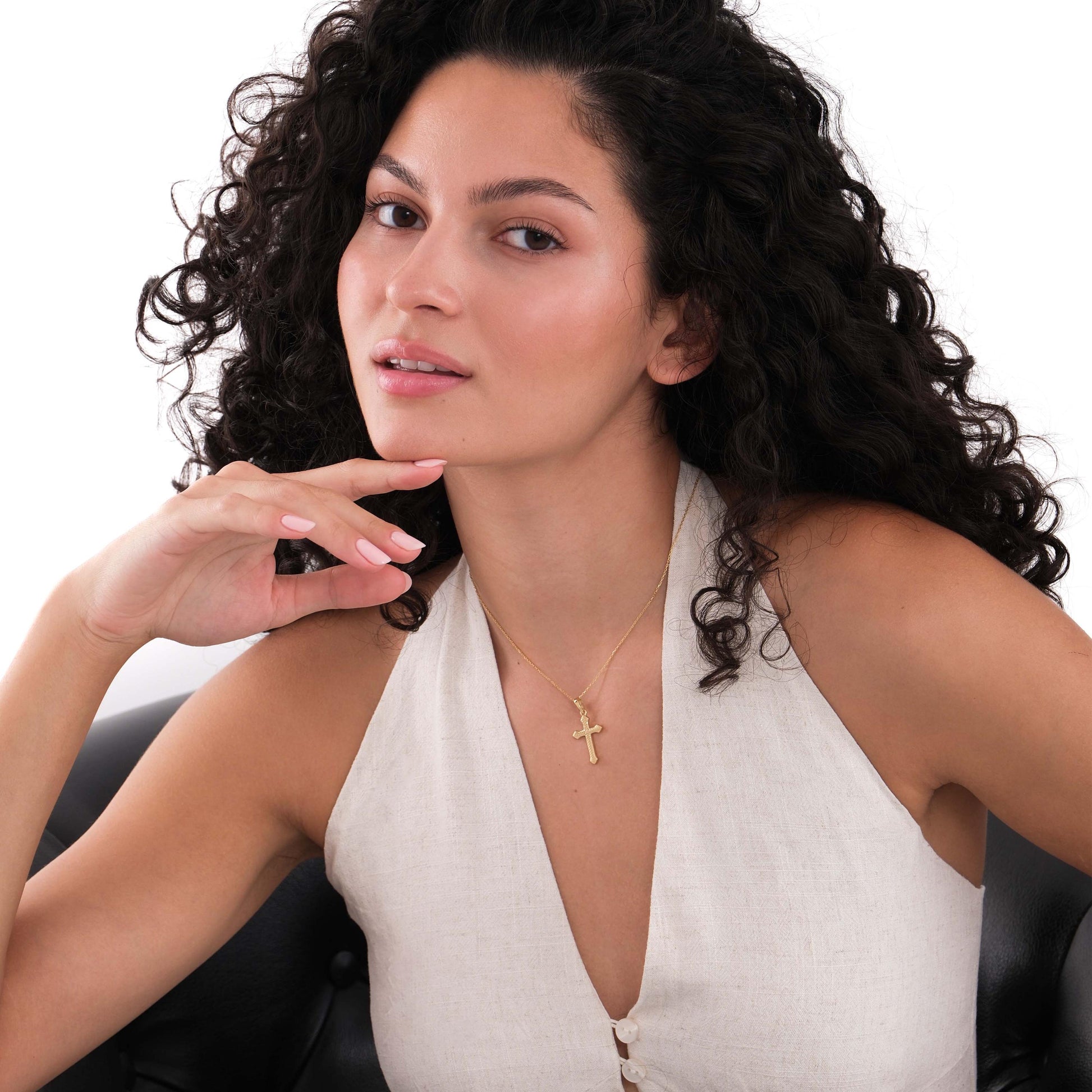 Fashionable 18K gold vermeil cross necklace worn by a woman posing in a sleeveless linen blouse.
