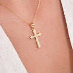 Close-up of an 18K gold vermeil cross necklace for women, resting on the chest over a light V-neck top.