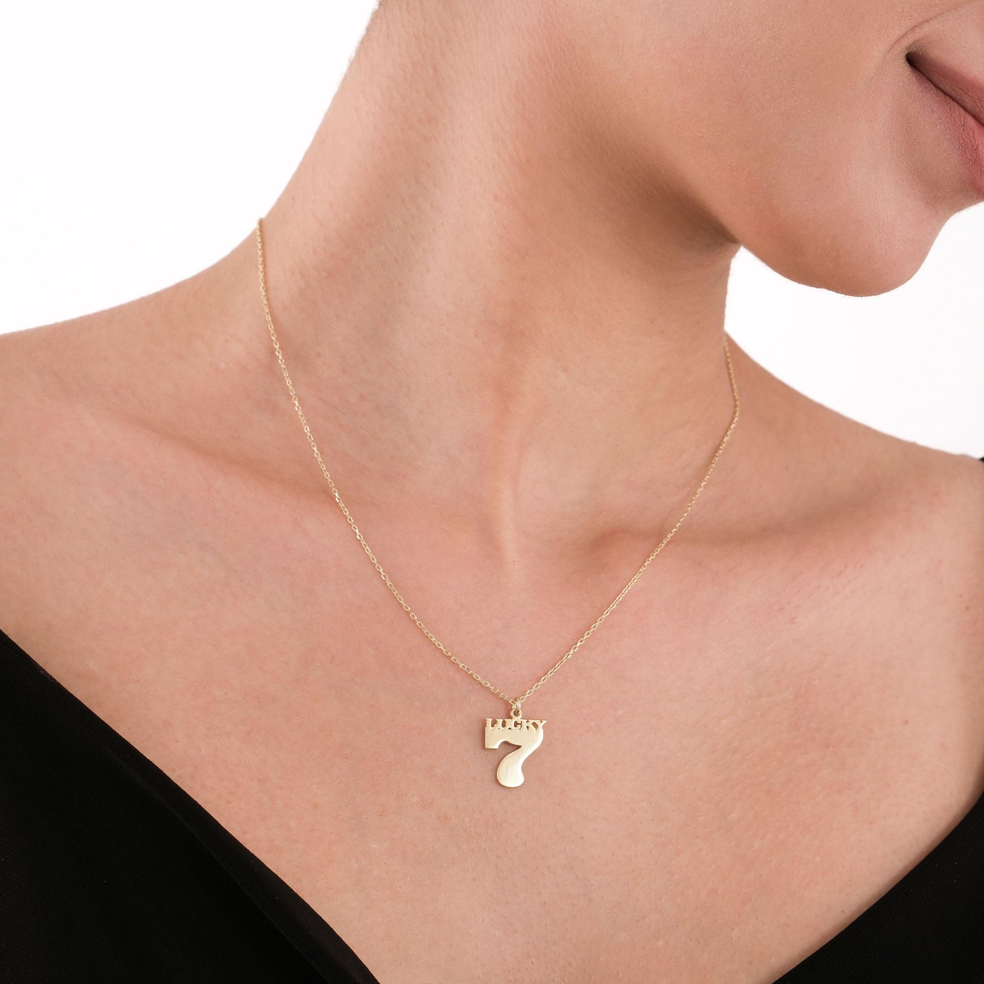 A minimalist 14K gold lucky number 7 necklace displayed on a fine gold chain.
