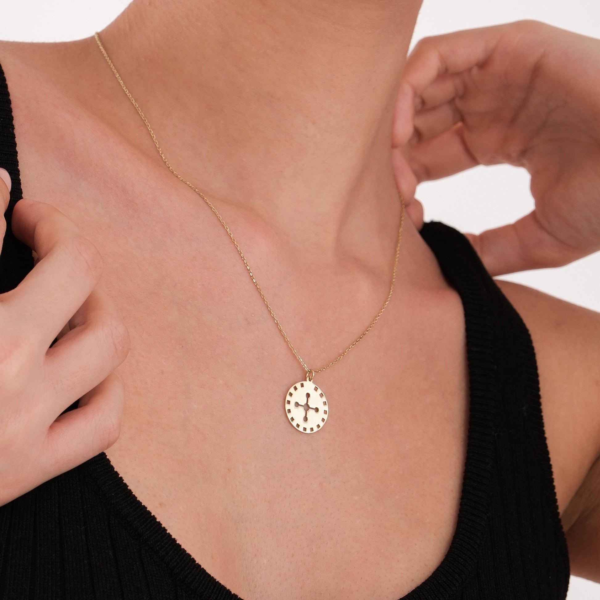 Minimalist display of the 14K solid gold solar cross necklace placed on a white textured surface.