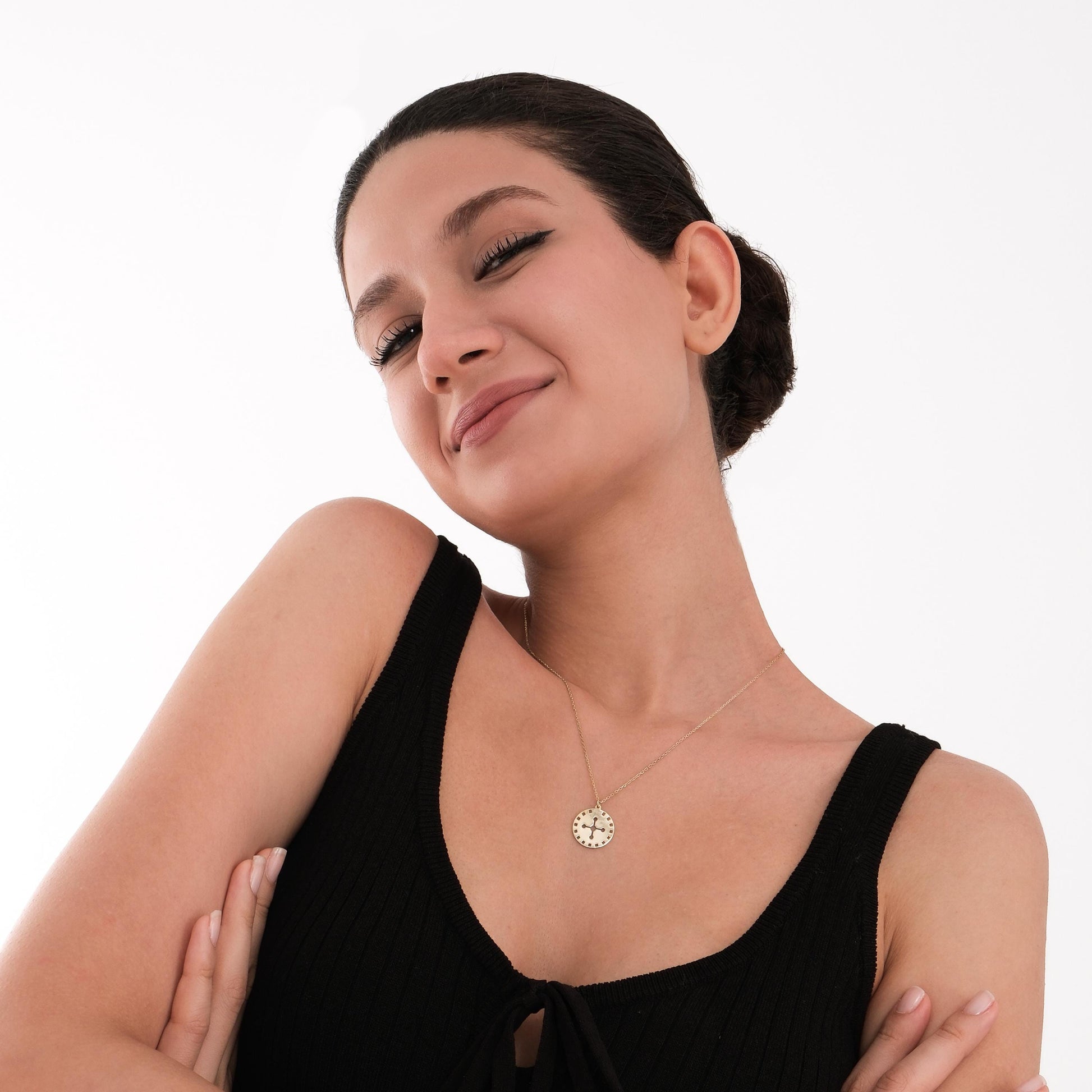 The 14K solid gold solar cross necklace pendant shown up close, revealing its radial, cut-out pattern.