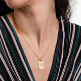 Elegant 18K gold vermeil handwriting necklace styled on a woman wearing a striped v-neck dress, highlighting the engraved pendant.