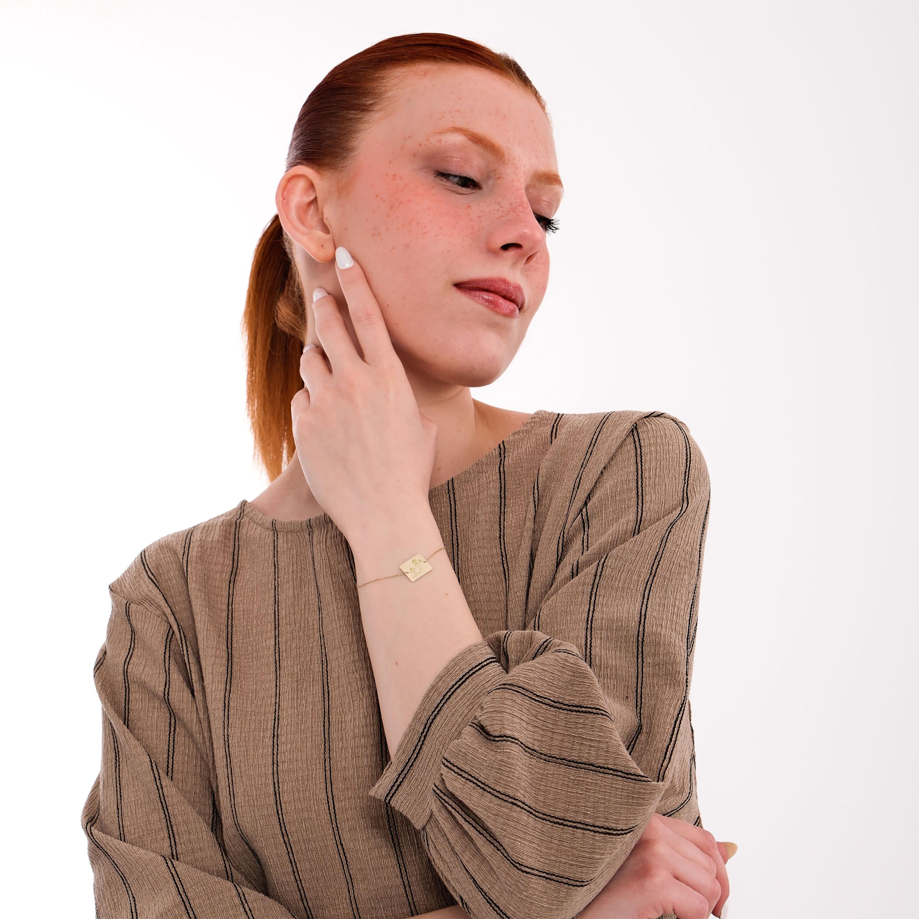 A delicate 14K solid gold Kids Handwriting Bracelet is showcased as the woman tucks her hair behind her ear.