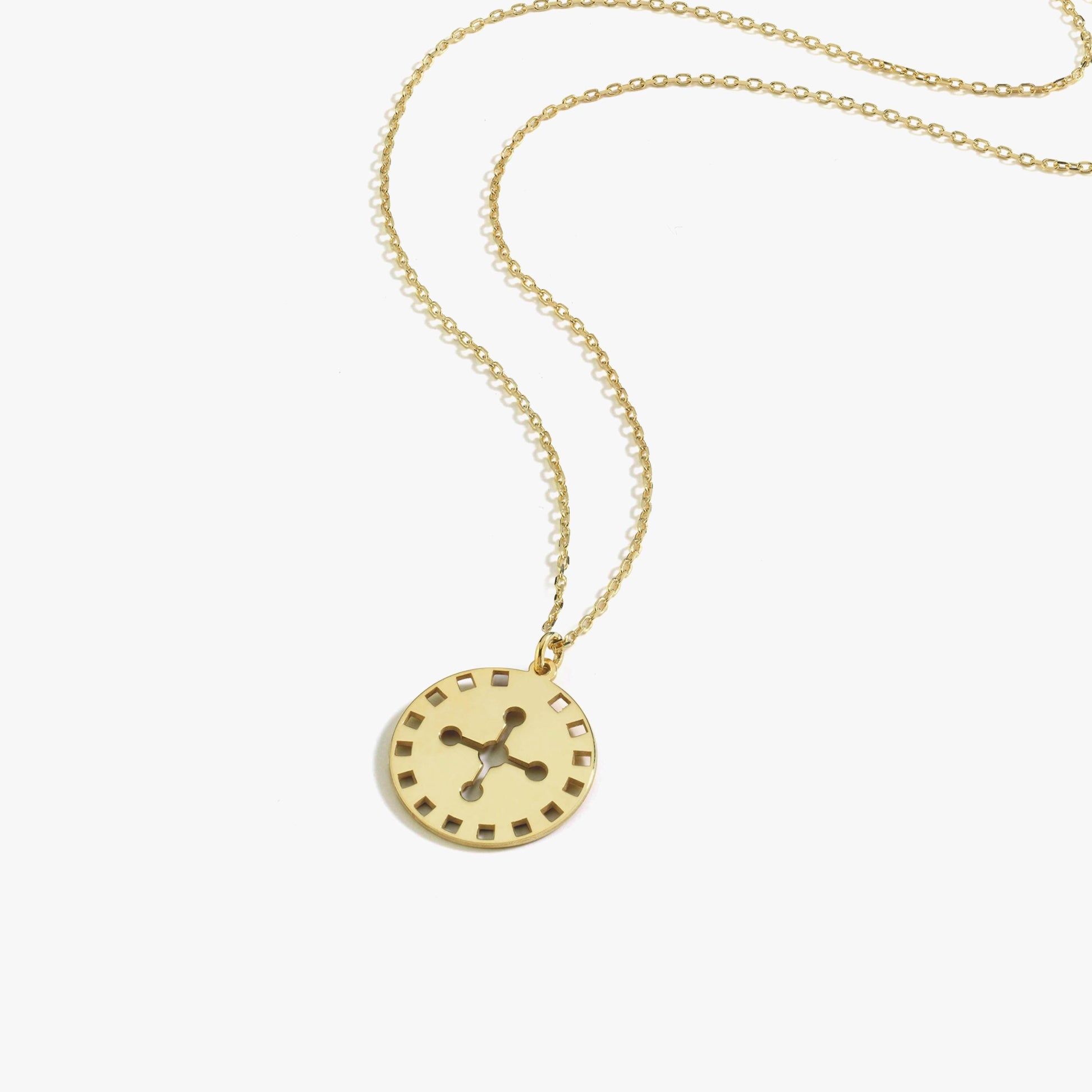 Close-up of the 14K solid gold solar cross necklace pendant resting against the model’s collarbone.