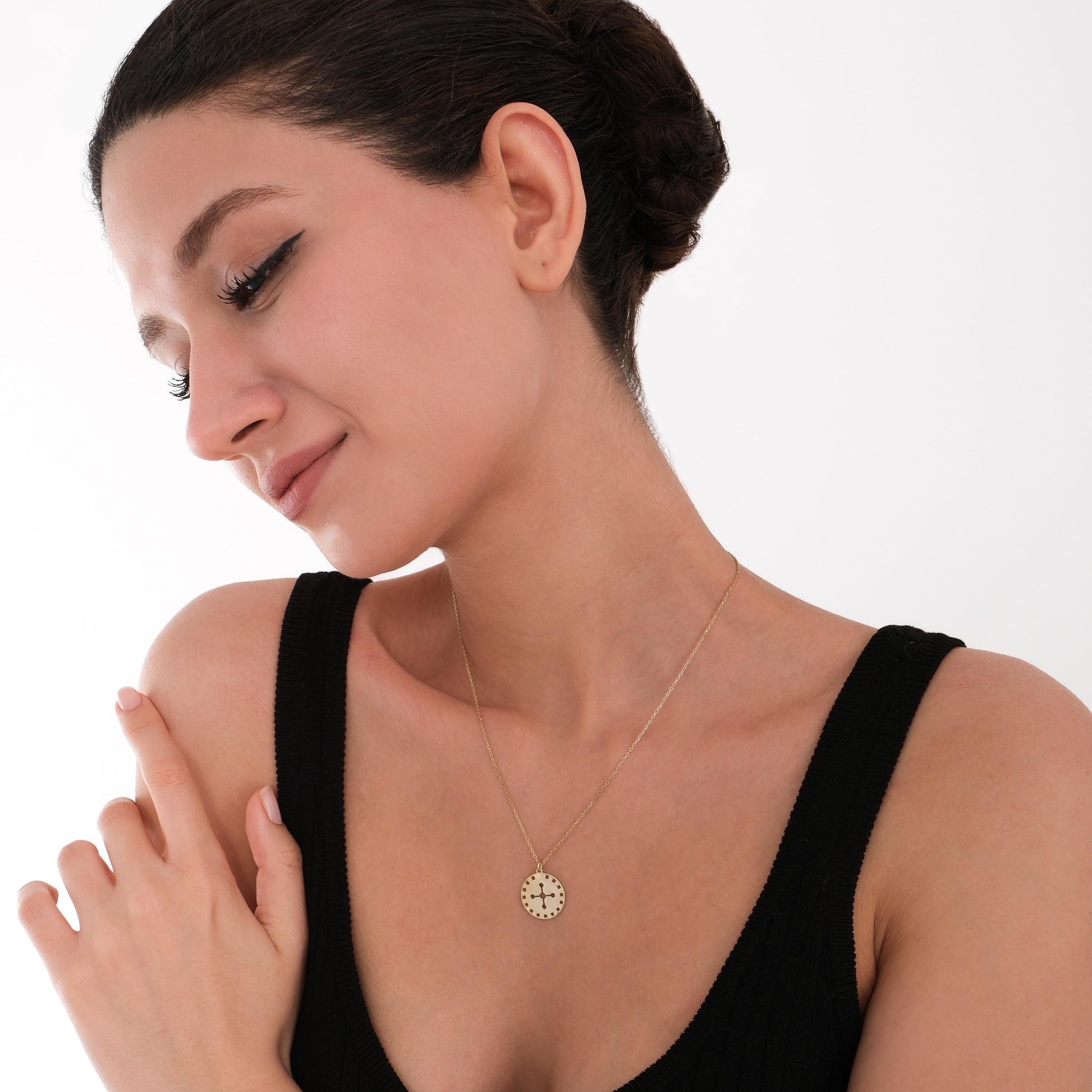 A woman showcasing the 14K solid gold solar cross necklace layered with two other delicate necklaces.