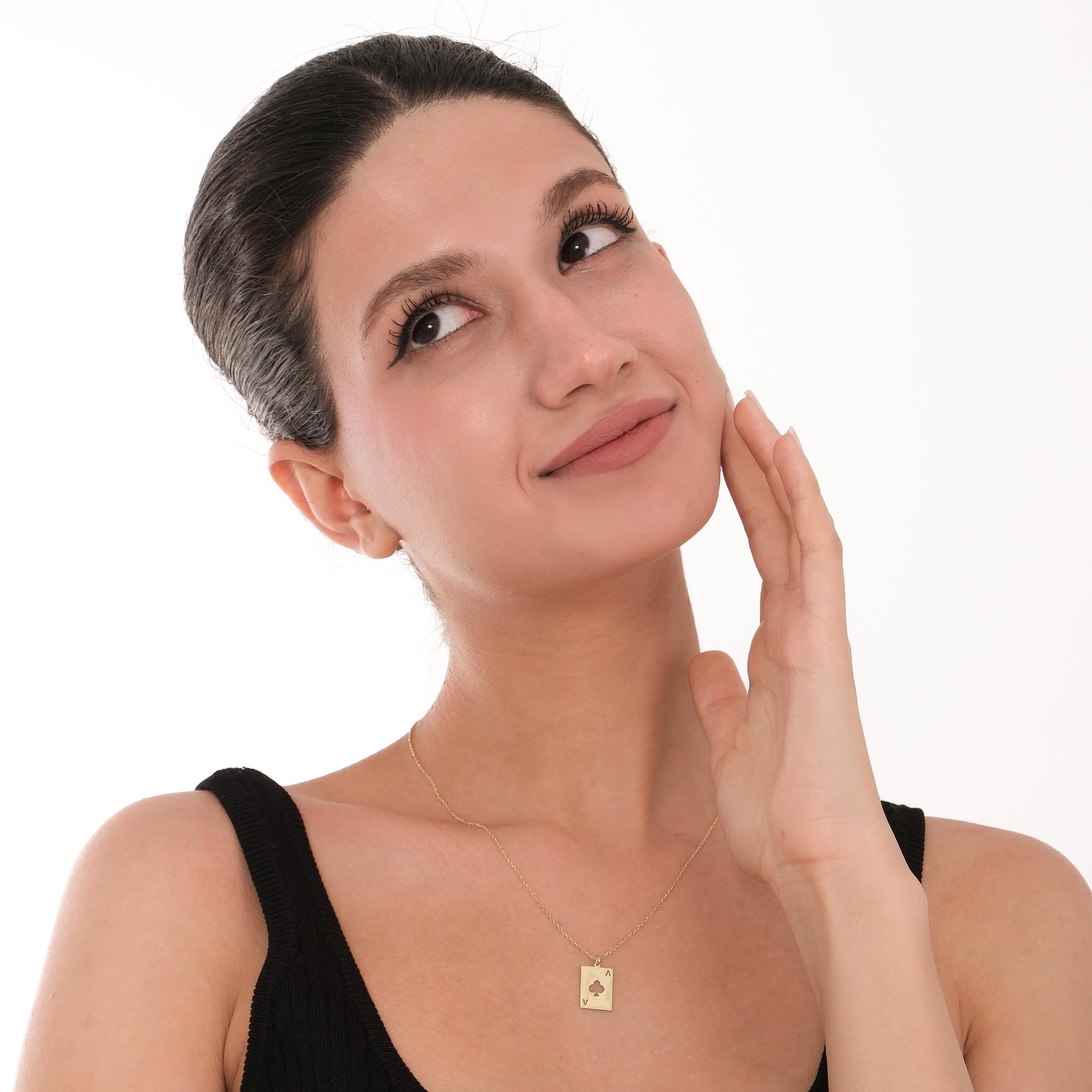 Smiling woman wearing a 14K Solid Gold Playing Card Necklace, reaching toward the camera.
