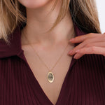 Woman posing with a 14K solid gold fingerprint necklace and her hand on her shoulder.