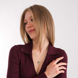 Close-up of a woman wearing a 14K solid gold fingerprint necklace with her arms crossed.