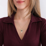 Woman holding her 14K solid gold fingerprint necklace while looking to the side.