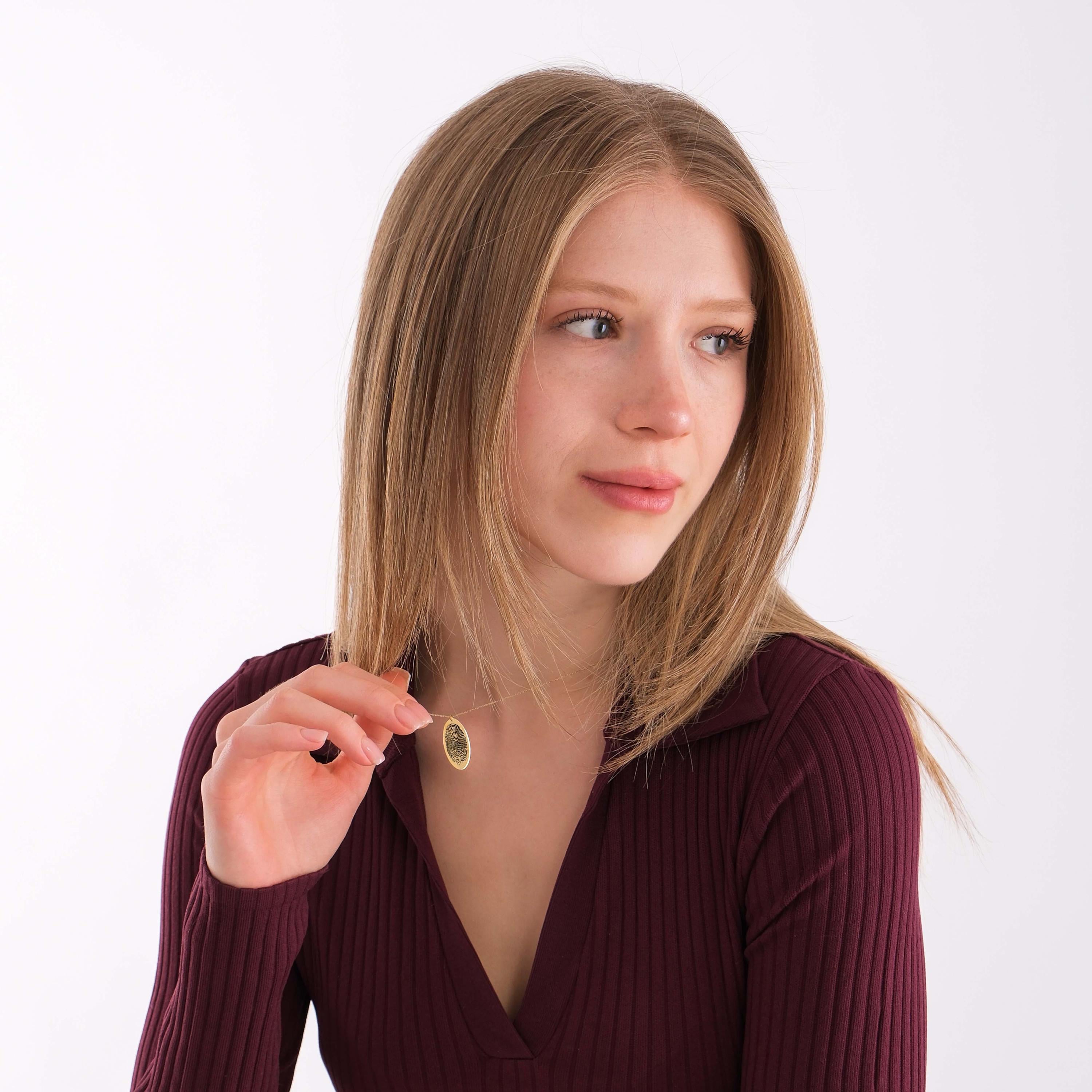 Woman wearing a 14K solid gold fingerprint necklace with a burgundy ribbed top.