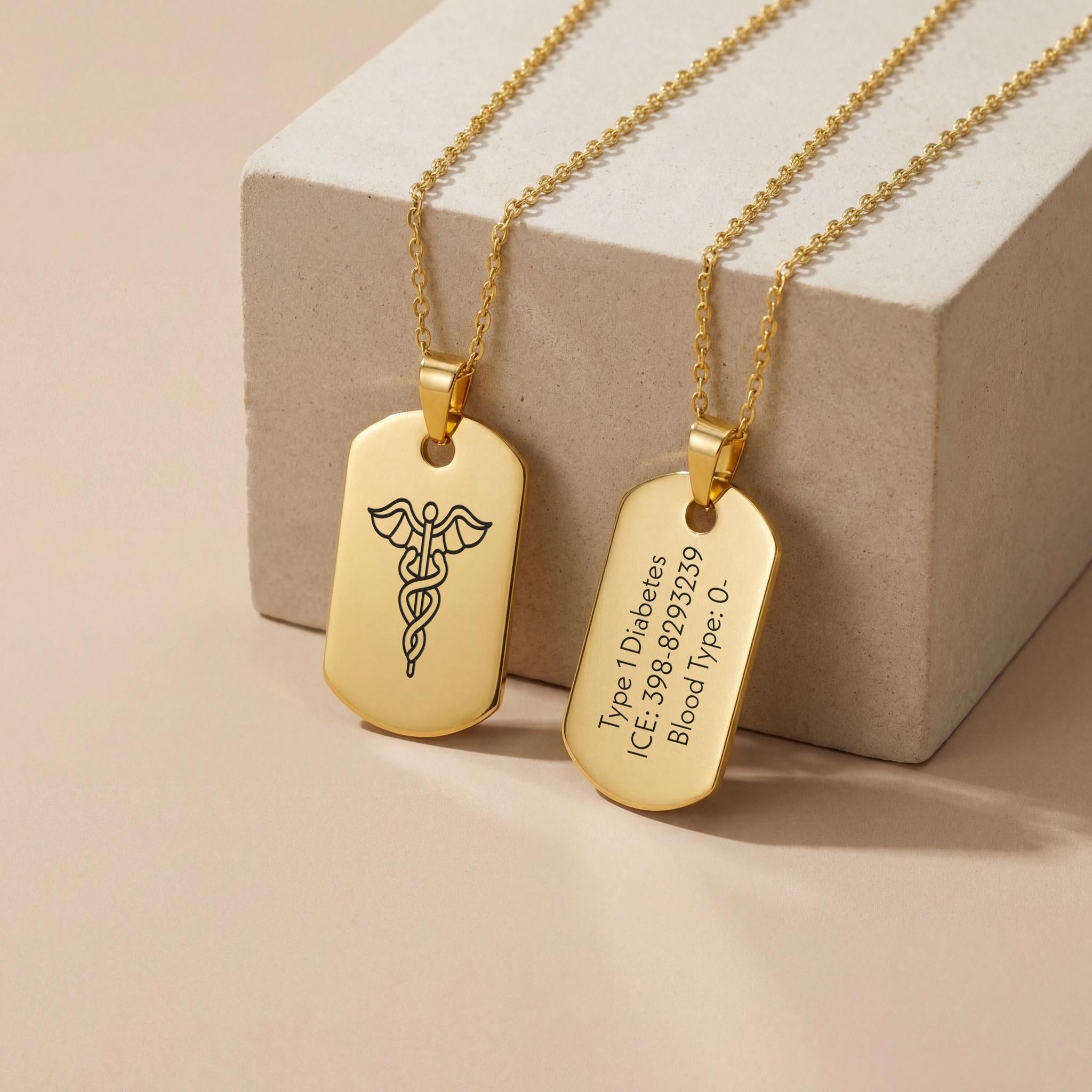 18K Gold Vermeil Personalized Medical ID Necklace with engraved caduceus symbol and custom medical information on polished dog tag pendants displayed on neutral stone block.