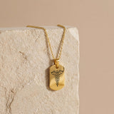 18K Gold Vermeil Personalized Medical ID Necklace with caduceus symbol engraving hanging on textured stone background.