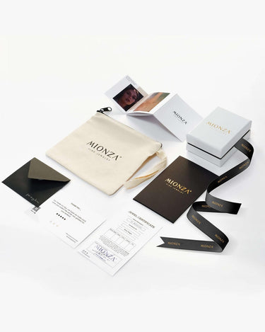 This image displays an array of packaging materials and printed items from "Mionza." Visible items include branded boxes, a pouch, ribbon, business cards, an envelope, a receipt, a thank you card featuring a Bow Ring design in 14K Solid Gold and a booklet—all with a sleek and professional aesthetic.