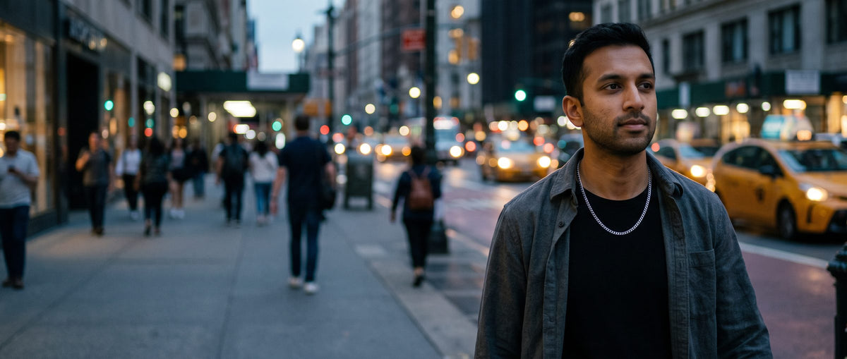 Man in a denim jacket wearing a silver chain on a busy New York street