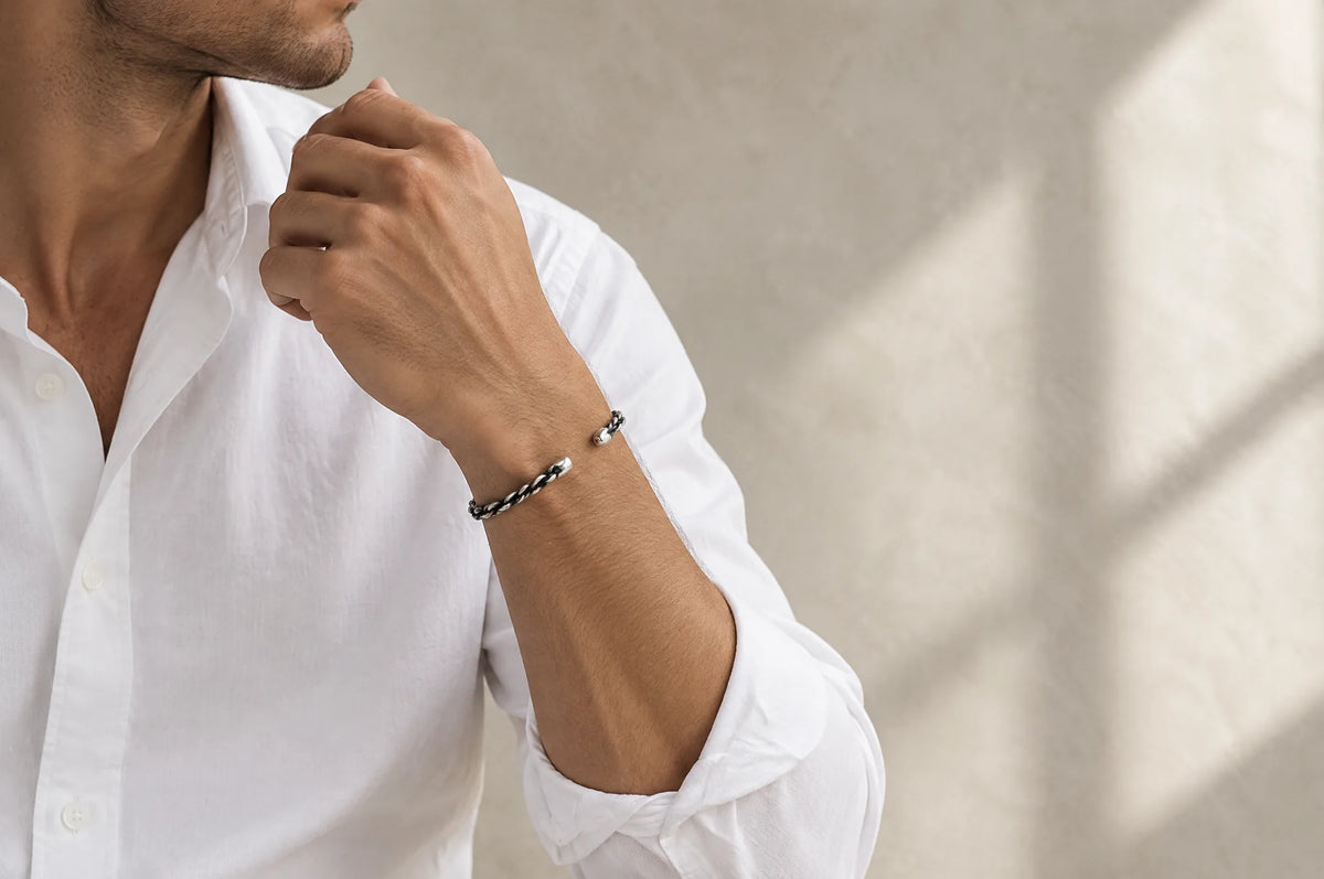 Man in a white shirt wearing a silver bracelet in window light