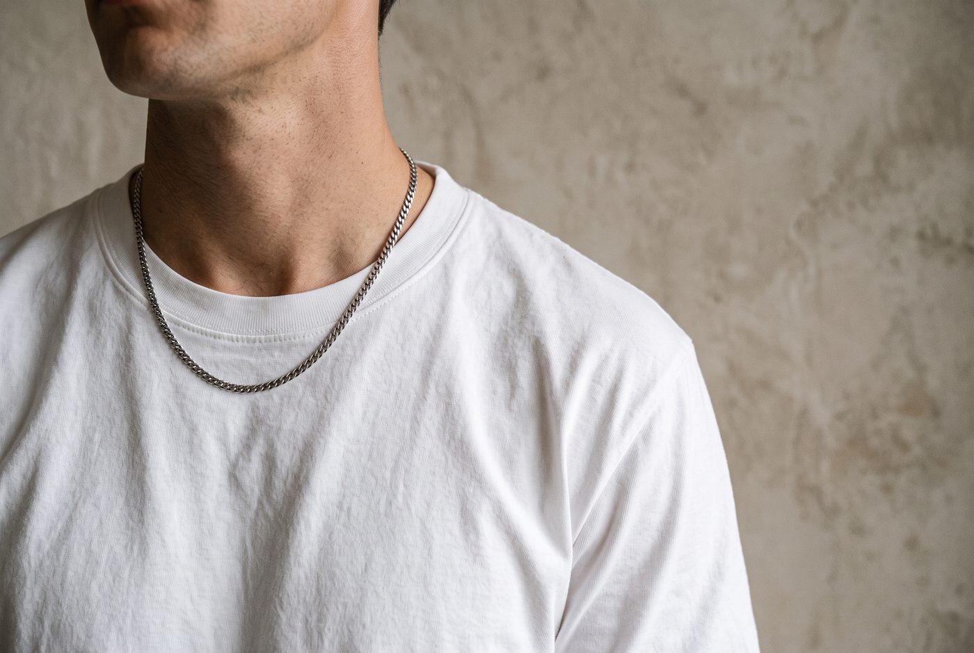 Man in a white T-shirt wearing a silver chain necklace