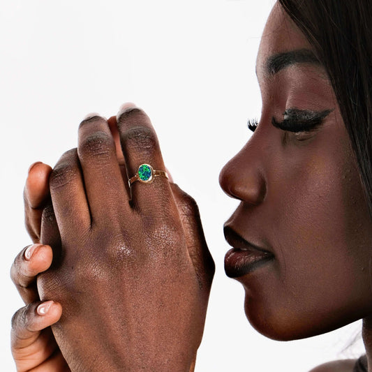 Close-up of a woman's face and hand with a ring on a white background