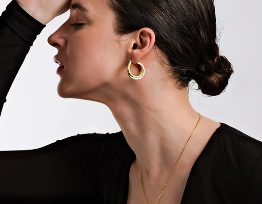 Elegant woman wearing gold hoop earrings and gold necklace with hair in a bun – minimalist jewelry gift idea for Mother's Day