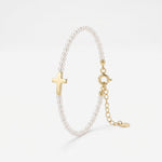 Pearl cross bracelet with a row of small pearls and a polished sideways gold cross, a pearl and gold bracelet with extender
