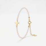 Pearl cross bracelet with a row of small pearls and a polished sideways gold cross, a pearl and gold bracelet with extender