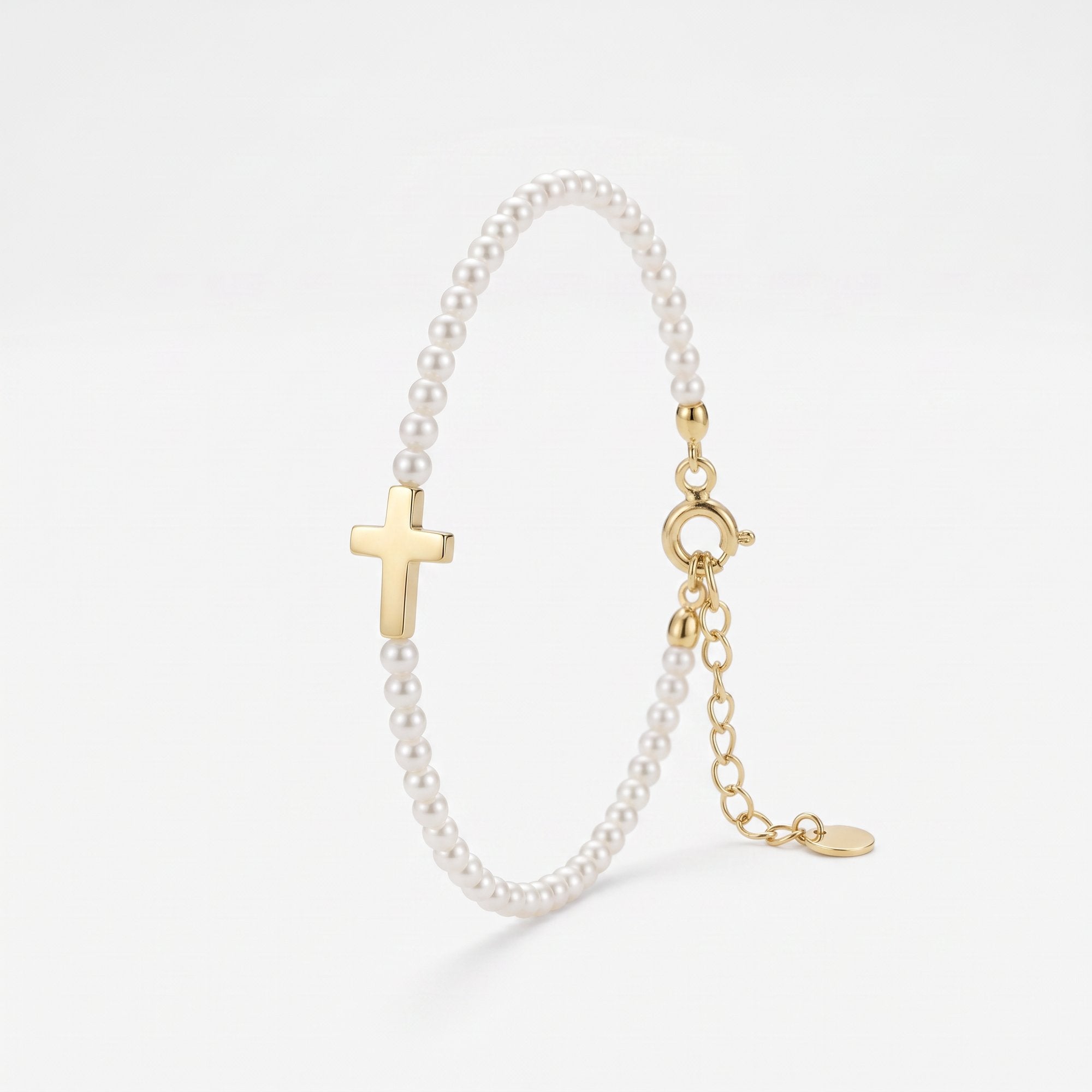 Pearl cross bracelet with a row of small pearls and a polished sideways gold cross, a pearl and gold bracelet with extender